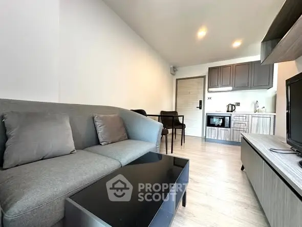 Modern living room with sleek furniture and open kitchen layout in a stylish apartment.