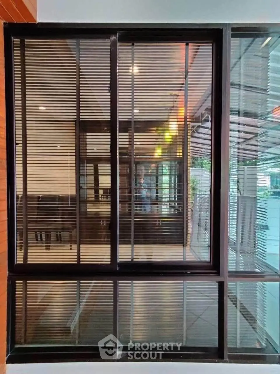 Modern glass window with blinds offering a sleek view of interior and exterior spaces.