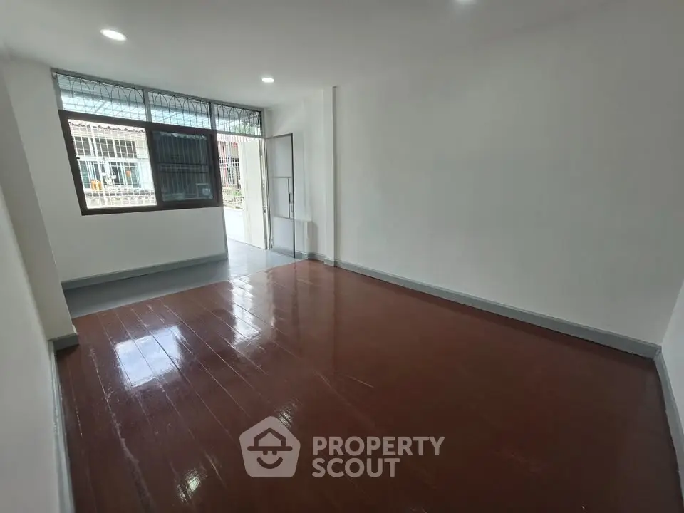 Spacious and bright living room with polished wooden floors and large window.