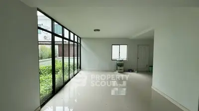 Spacious empty room with large windows and garden view, perfect for customization.