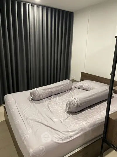 Cozy bedroom with elegant curtains and stylish bedding in modern apartment.