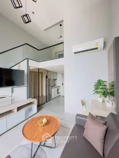 Modern living room with loft design, sleek furniture, and open kitchen layout in a stylish apartment.
