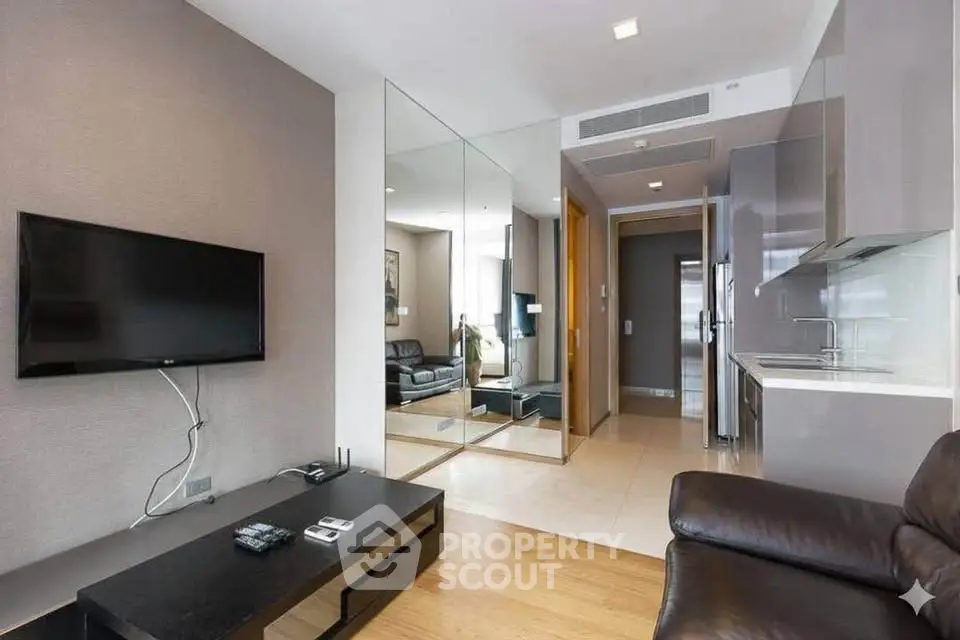 Modern living room with sleek furniture and mirrored wall in a stylish apartment.