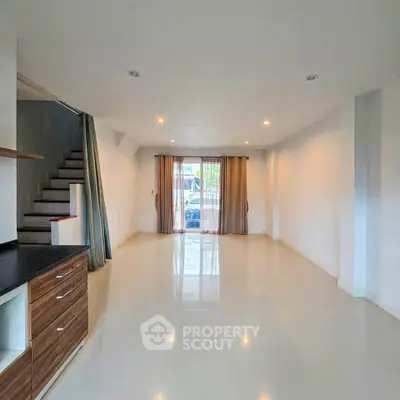 Spacious modern living room with sleek flooring and natural light, ideal for contemporary living.