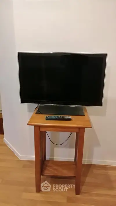 Cozy living room setup with a sleek TV on a wooden stand, perfect for entertainment.