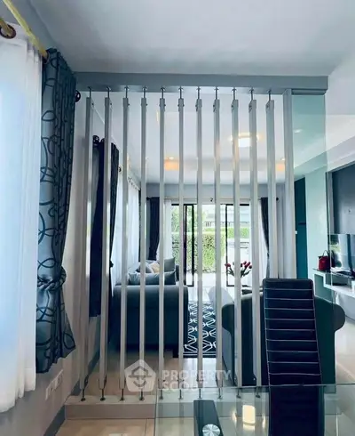 Modern living room with stylish partition and elegant decor, featuring large windows and cozy seating area.
