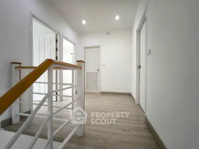 Bright and spacious hallway with modern wooden flooring and white walls, leading to multiple rooms.
