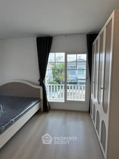 Bright bedroom with large window and wardrobe, offering a serene view and ample natural light.