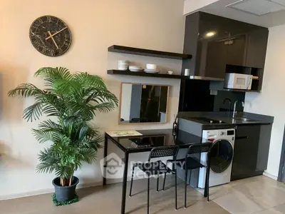 Modern kitchen with sleek black cabinets, integrated appliances, and stylish dining area.