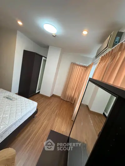 Spacious bedroom with wooden flooring and large windows for natural light.