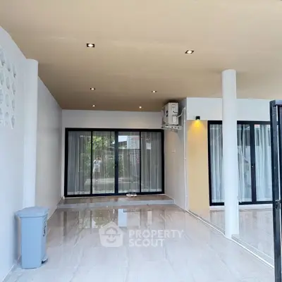 Spacious modern living room with large windows and sleek tile flooring, perfect for natural light and open space.