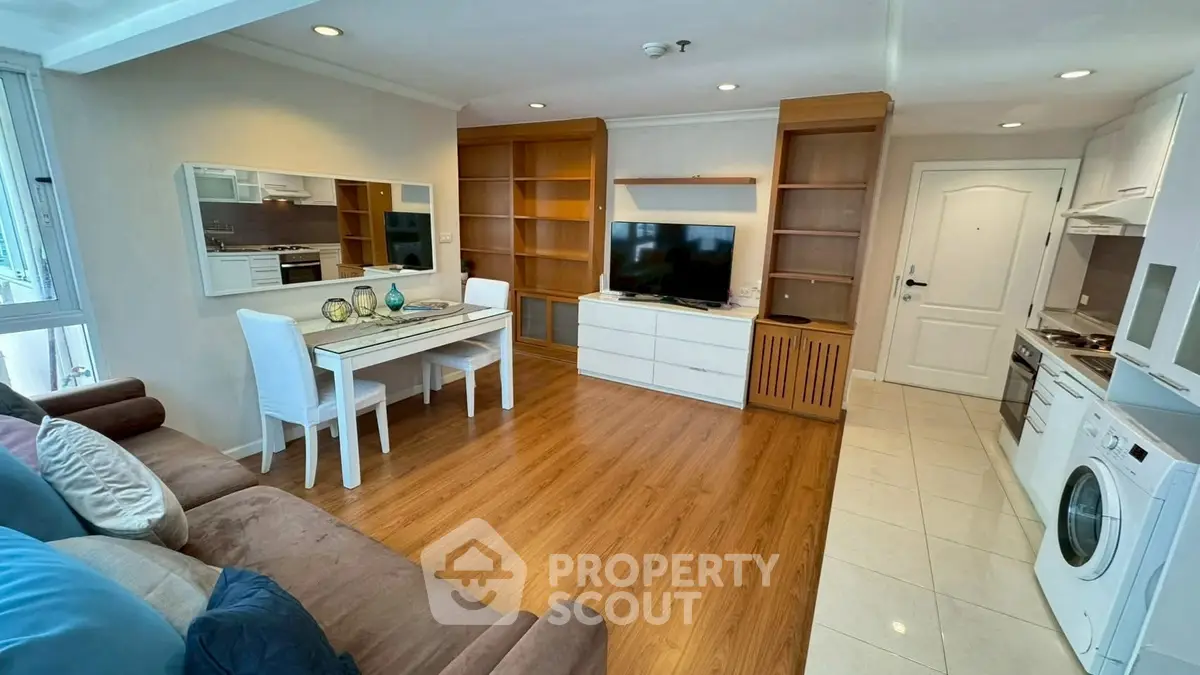 Charming living room with modern furniture and open kitchen layout, perfect for cozy gatherings.