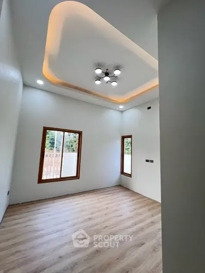 Modern empty room with stylish ceiling lights and wooden flooring, perfect for customization.