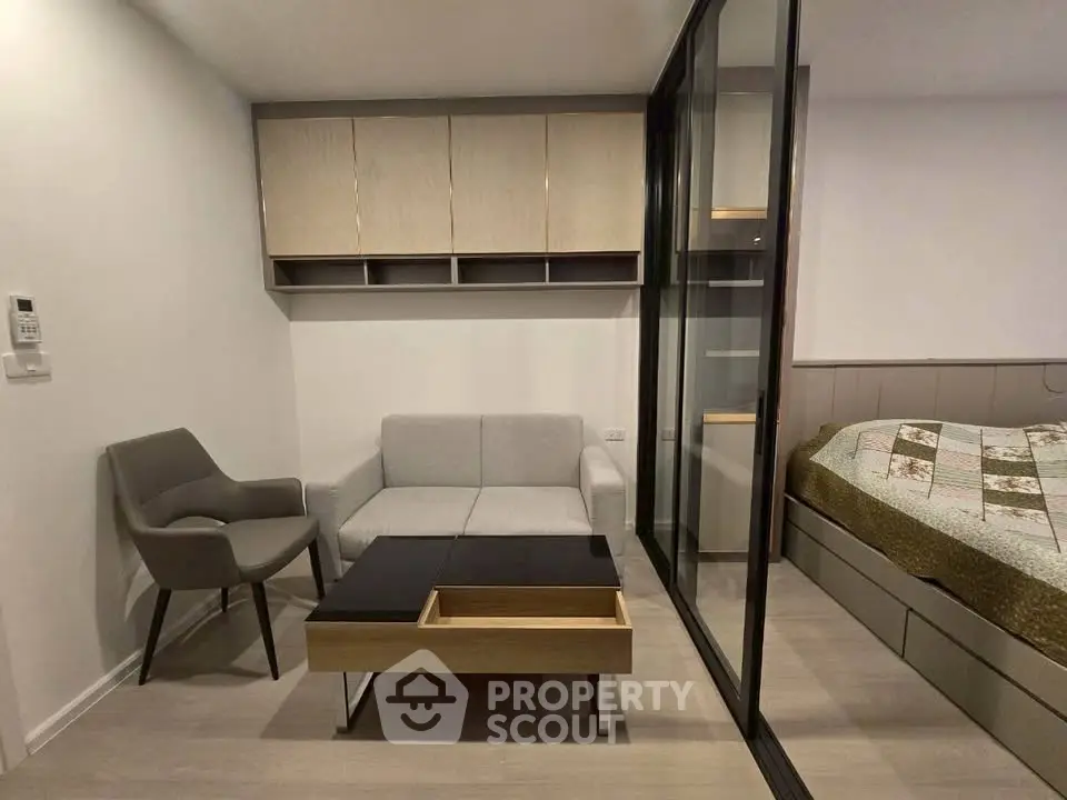 Modern studio apartment with cozy living area and bedroom separated by glass partition.
