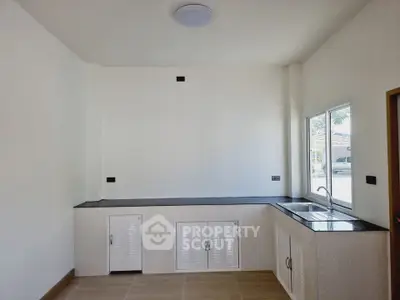 Minimalist kitchen with sleek countertops and large window for natural light.
