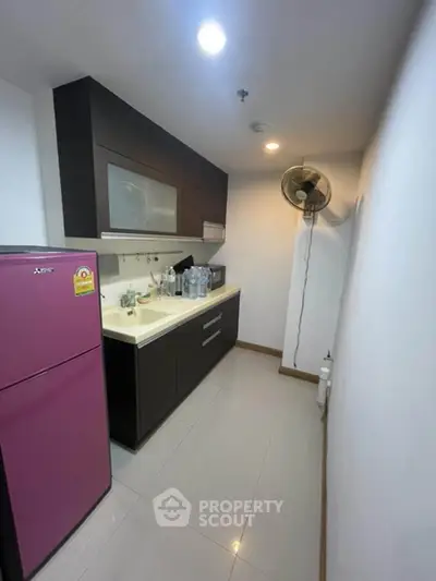 Modern kitchen with sleek cabinets and pink fridge in compact layout