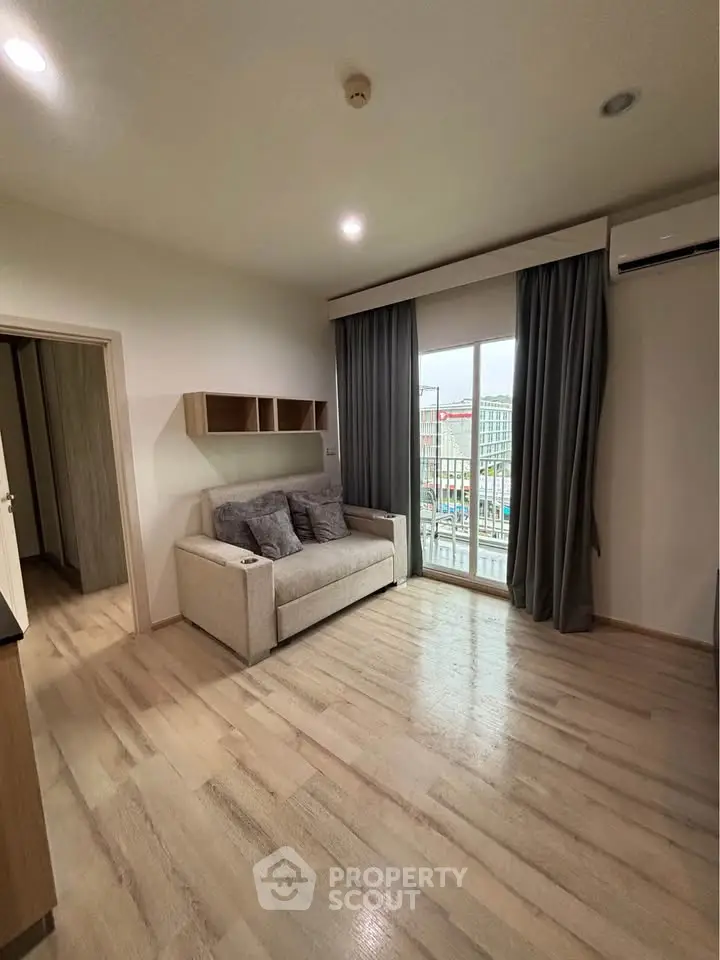 Modern living room with cozy sofa and large window offering city view, perfect for urban living.