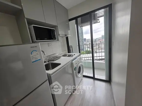 Modern kitchen with appliances and balcony view in urban apartment