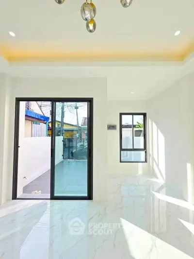 Bright modern living room with marble flooring and large sliding glass doors leading to a patio.