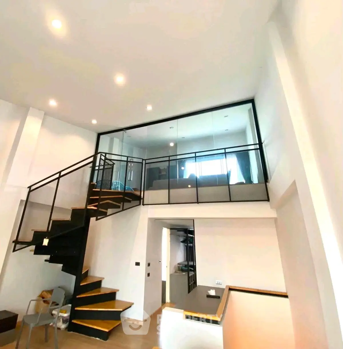 Modern duplex apartment with stylish staircase and glass railing, featuring open layout and bright lighting.