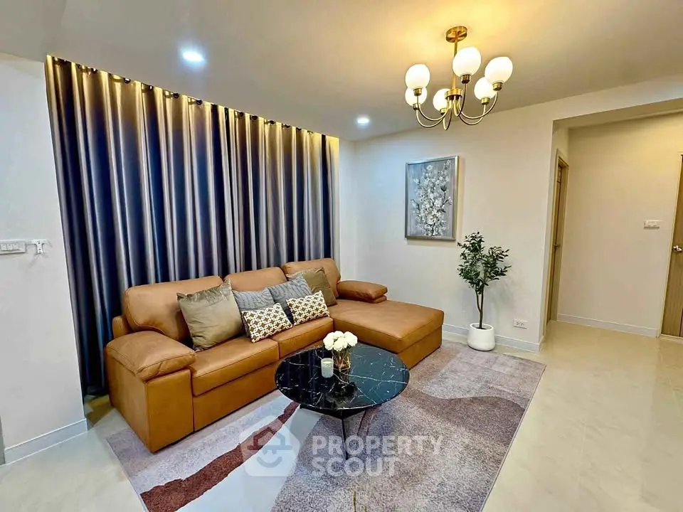 Elegant living room with modern decor, featuring a stylish leather sofa, chic chandelier, and artistic wall art.