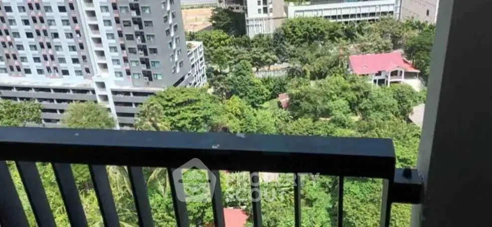 Stunning balcony view overlooking lush greenery and modern buildings in urban setting.