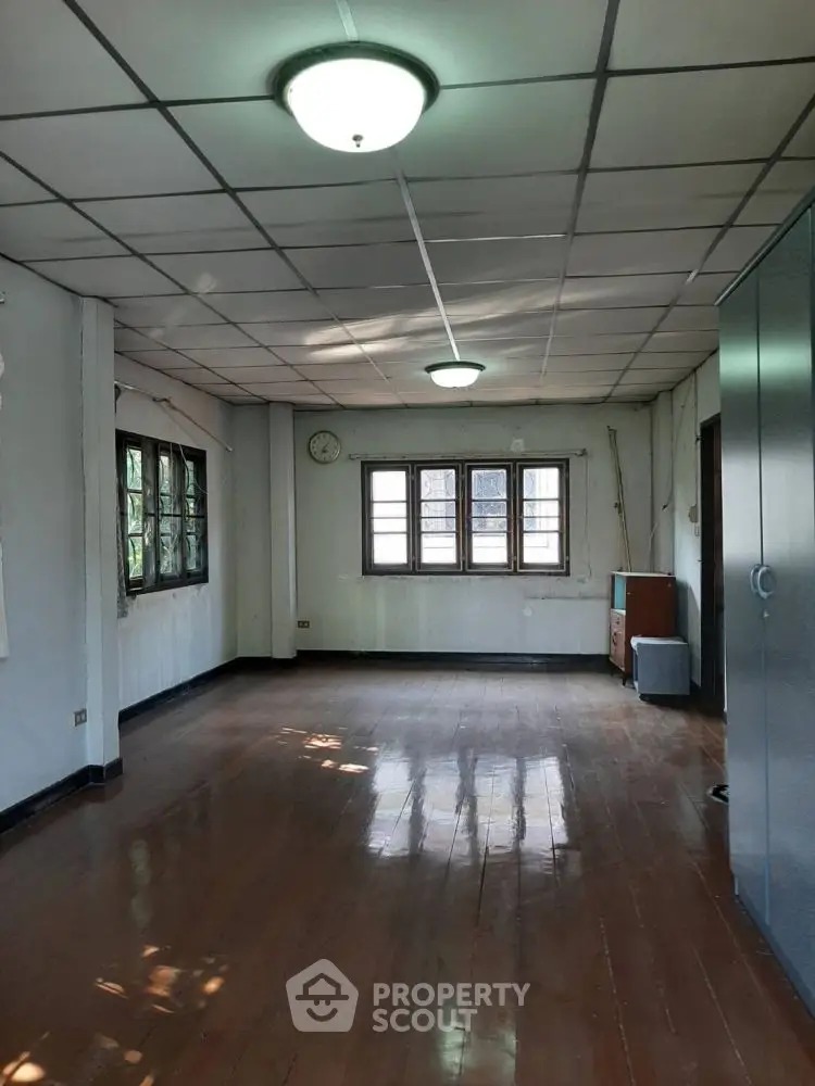 Spacious empty room with wooden floors and large windows, ideal for customization.