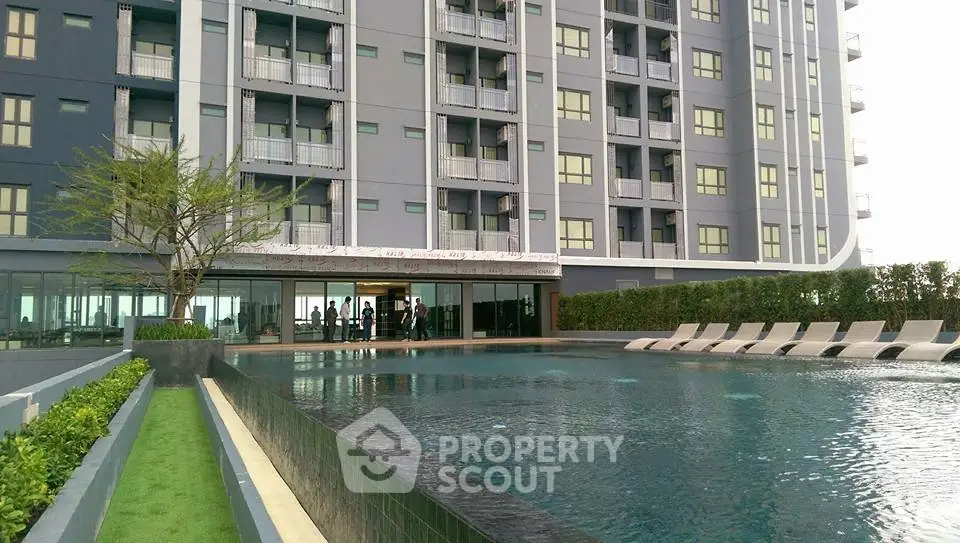 Modern apartment building with luxurious pool and landscaped surroundings.