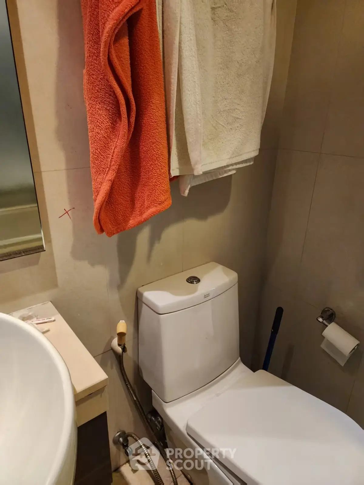 Compact bathroom with modern toilet and sink, featuring hanging towels for convenience.