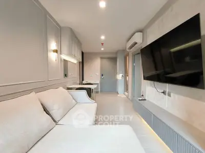 Modern living room with sleek design, large wall-mounted TV, and comfortable seating in a stylish apartment.