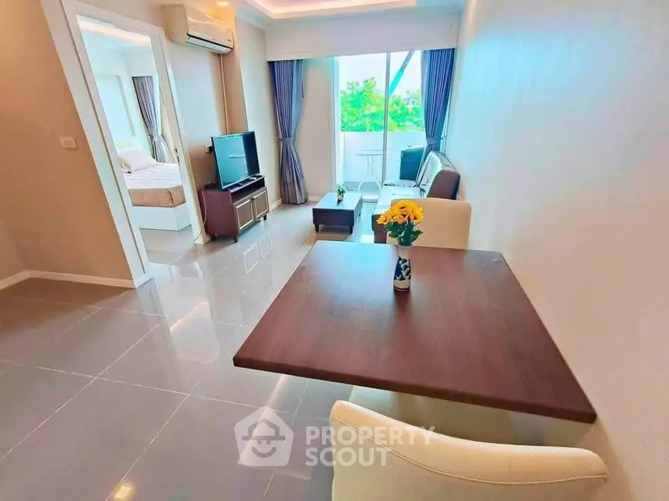 Modern living room with open layout and natural light, featuring stylish furniture and a view of the bedroom.
