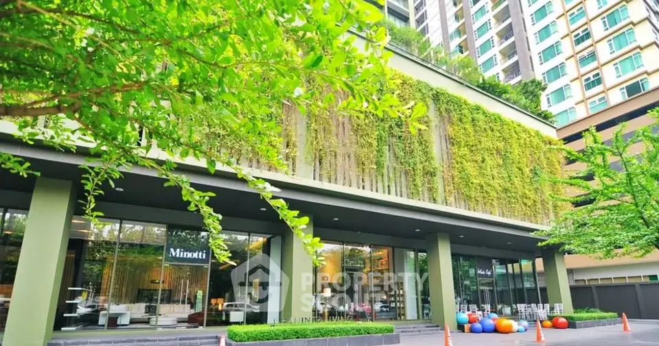 Modern building exterior with lush greenery and large windows in urban setting.