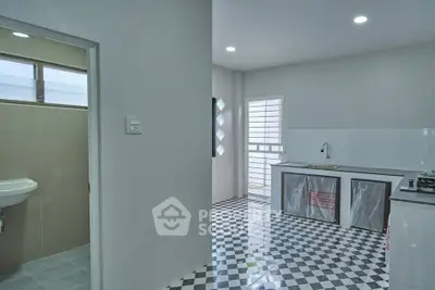 Modern kitchen with checkered floor and adjacent bathroom in a bright open space.