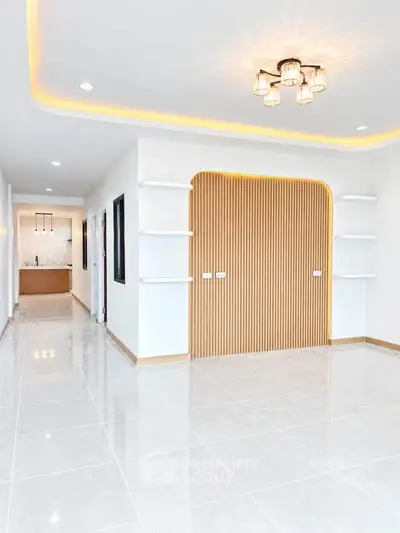 Spacious modern living room with elegant lighting and open layout leading to a sleek kitchen.