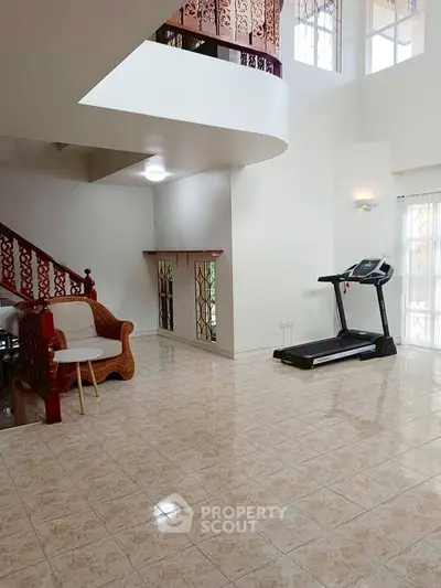Spacious living area with treadmill and elegant staircase, perfect for modern living.