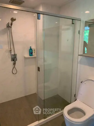 Modern bathroom with glass shower enclosure and sleek fixtures.