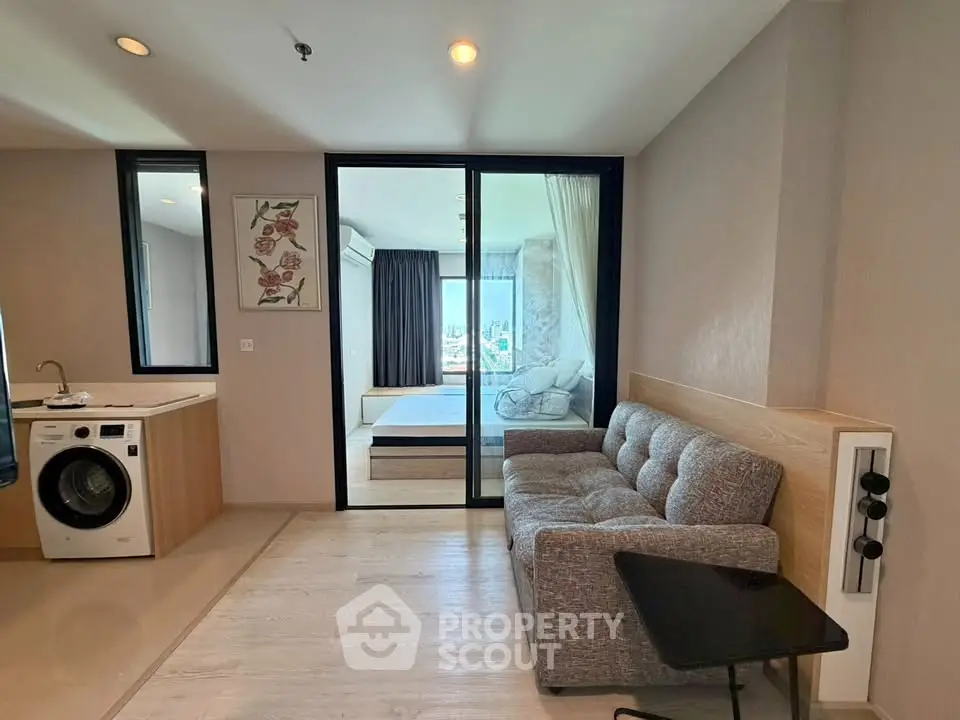 Modern living room with washing machine and view into bedroom