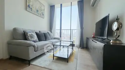 Modern living room with large windows and stylish decor in a high-rise apartment.