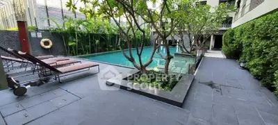 Luxurious modern pool area with lush greenery and sun loungers in a high-end residential complex.