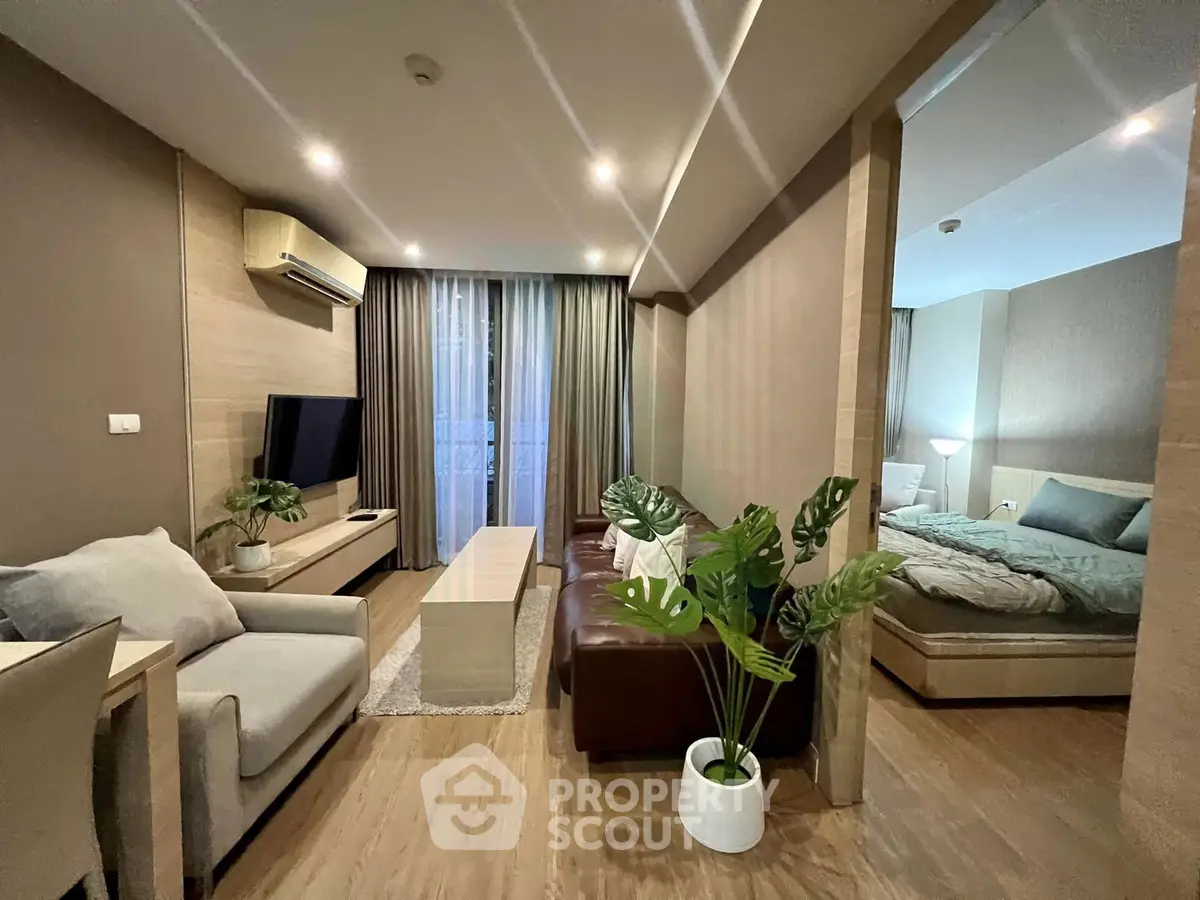 Modern living room with open layout and cozy bedroom, featuring stylish furniture and ambient lighting.