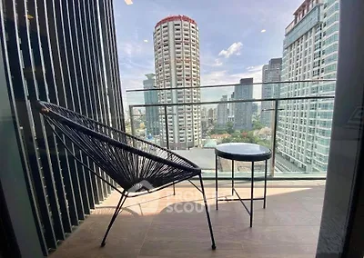 Stylish balcony with modern chair and table offering stunning city skyline views.