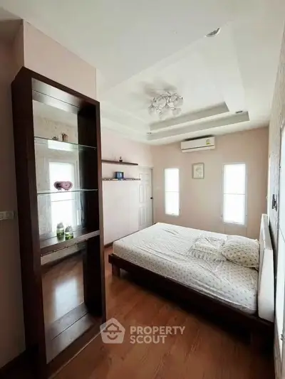 Spacious bedroom with modern decor and natural light, featuring a cozy bed and stylish shelving.