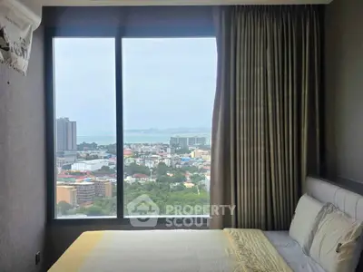 Luxurious bedroom with stunning city and ocean view from large window, featuring elegant decor and cozy bedding.