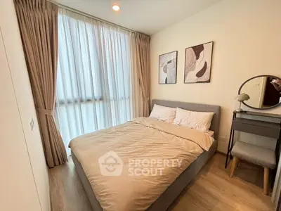Cozy bedroom with modern decor and natural light, featuring a comfortable bed and stylish artwork.