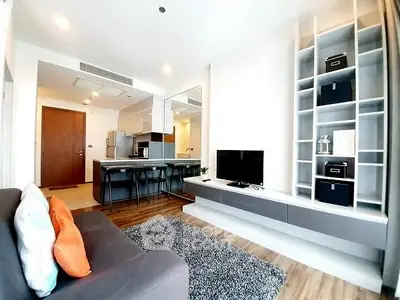 Modern living room with open kitchen and stylish shelving in a bright apartment.