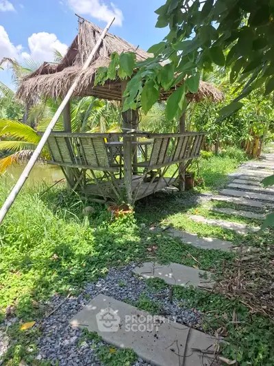 Charming outdoor gazebo in lush garden setting with stone pathway and tropical plants.