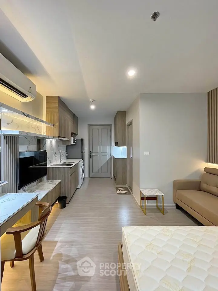 Modern studio apartment with open kitchen and cozy living area, featuring sleek design and natural light.