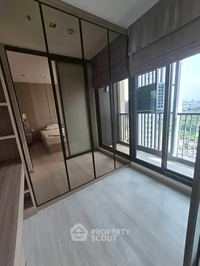 Modern bedroom with mirrored wardrobe and balcony view in high-rise apartment
