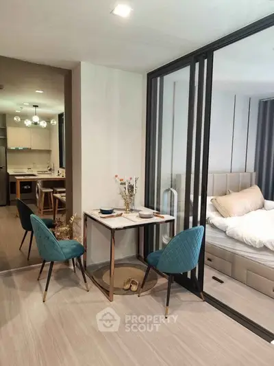 Modern studio apartment with open layout, featuring cozy dining area and stylish bedroom separated by glass partition.