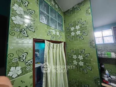 Vibrant green tiled bathroom with floral patterns and curtain partition